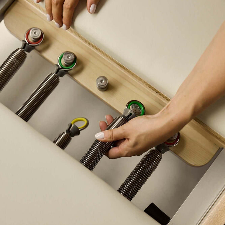 Hand changing spring of beige FOLD Reformer bed